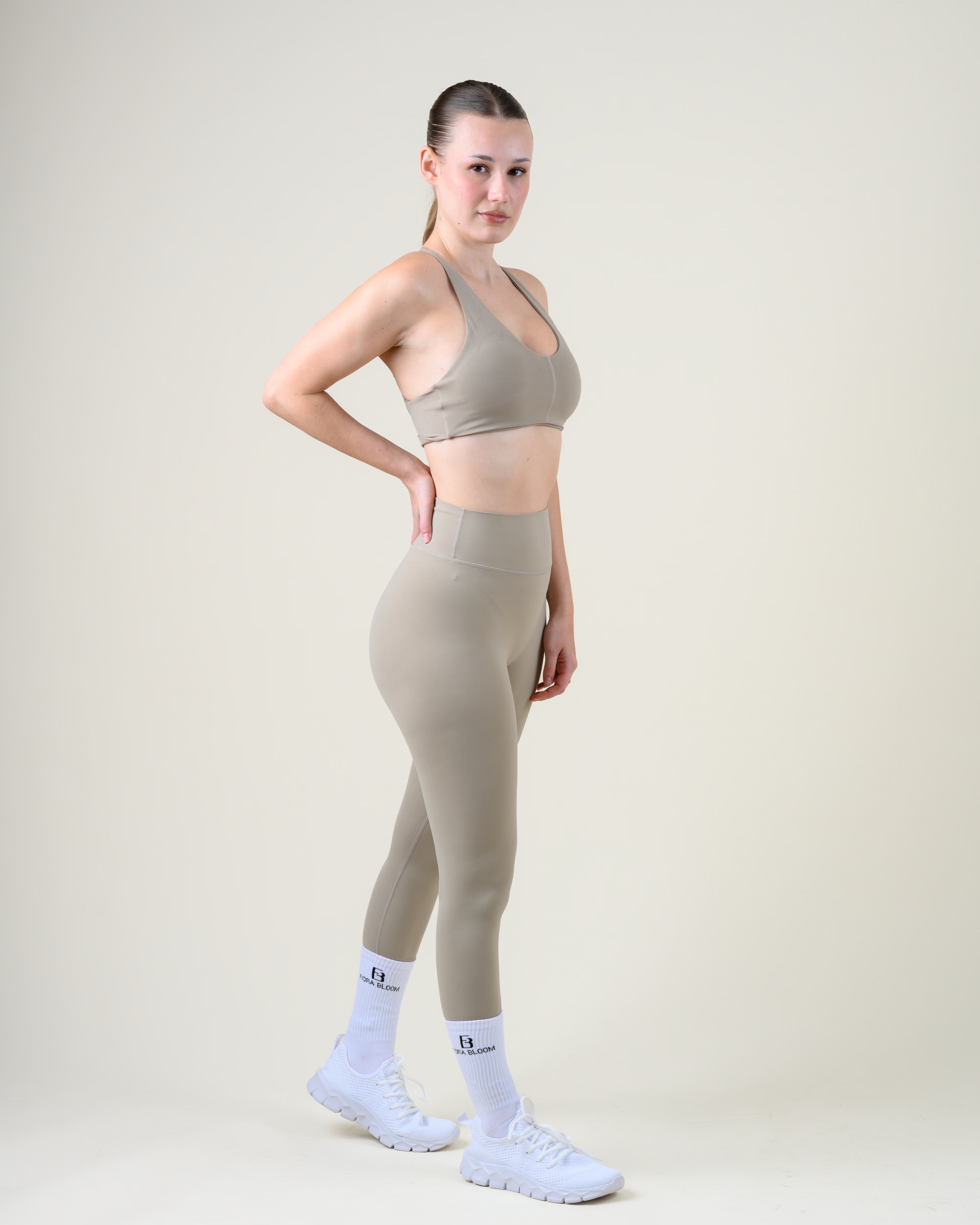 Soft Form Basic Top in Taupe von Fiora Bloom – Ganzkörper-Look von der Seite, kombiniert mit der Soft Form High-Waist Leggings in Taupe, weisse Socken und Sneaker.