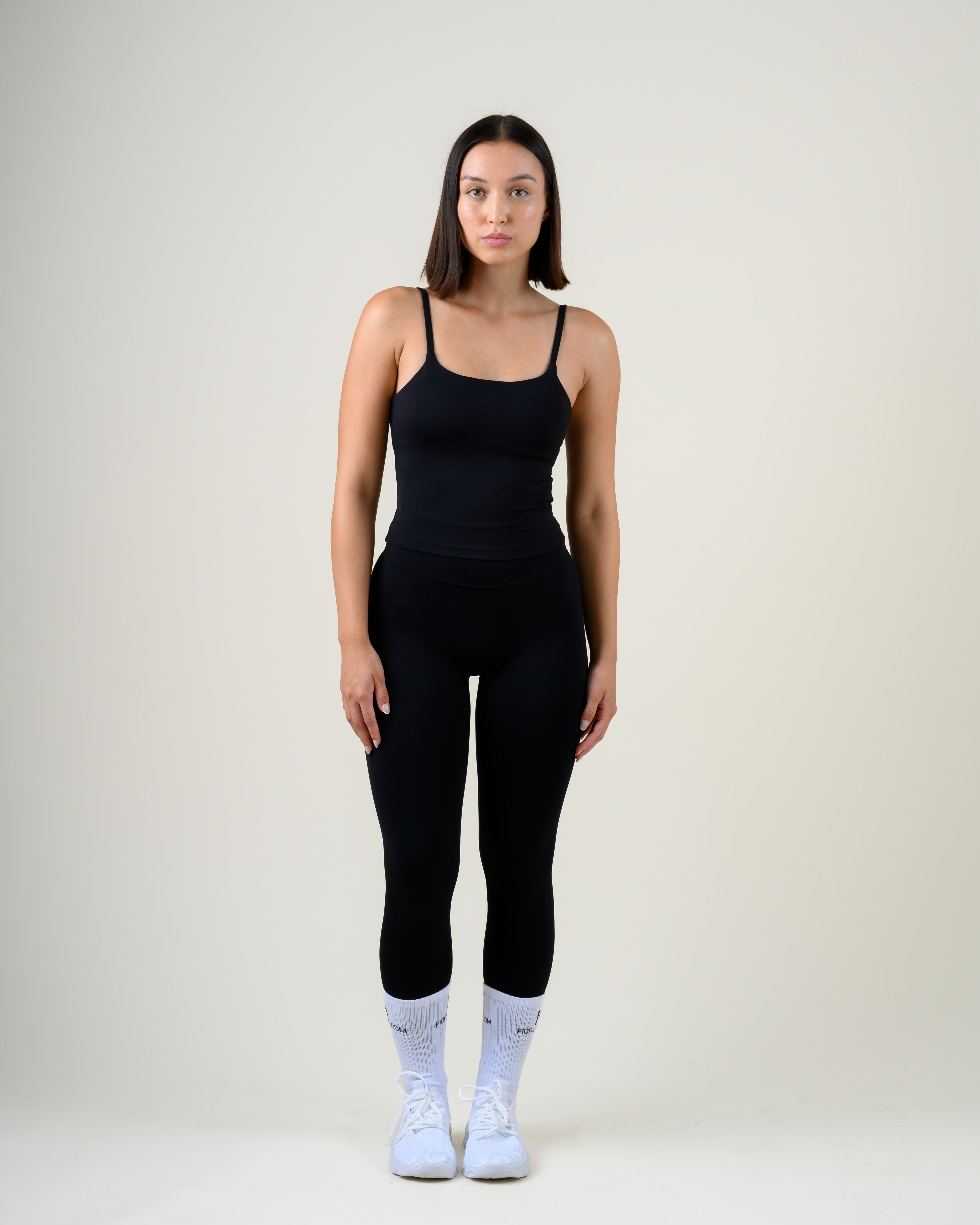 Soft Form High-Waist Leggings in Schwarz von Fiora Bloom – Ganzkörper-Look von vorne, kombiniert mit dem Soft Form Tanktop in Schwarz, weisse Socken und Sneaker.