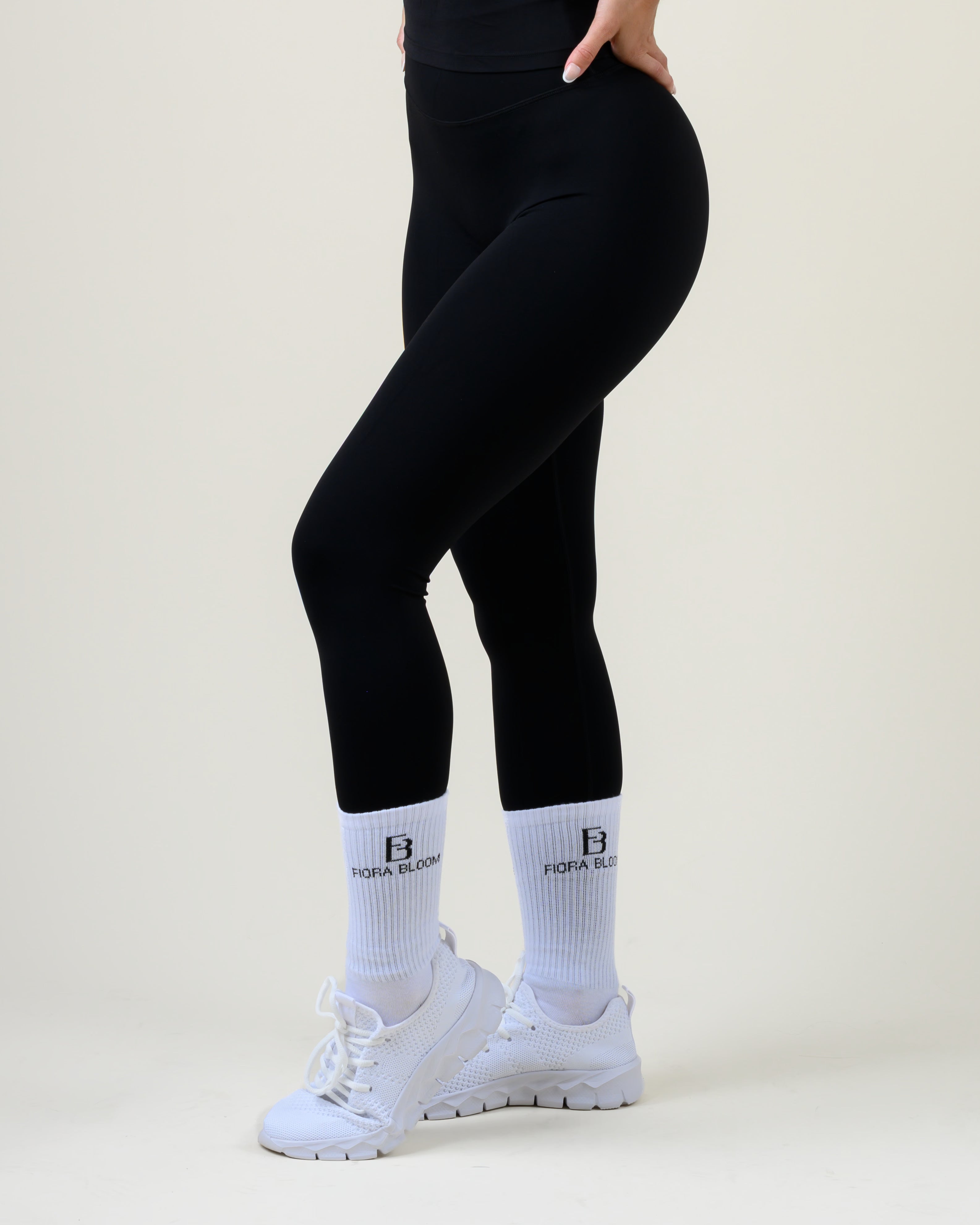 Soft Form High-Waist Leggings in Schwarz von Fiora Bloom – Seitenansicht in Bewegung, Bein angewinkelt, Sitz an Hüfte und Oberschenkel sichtbar.