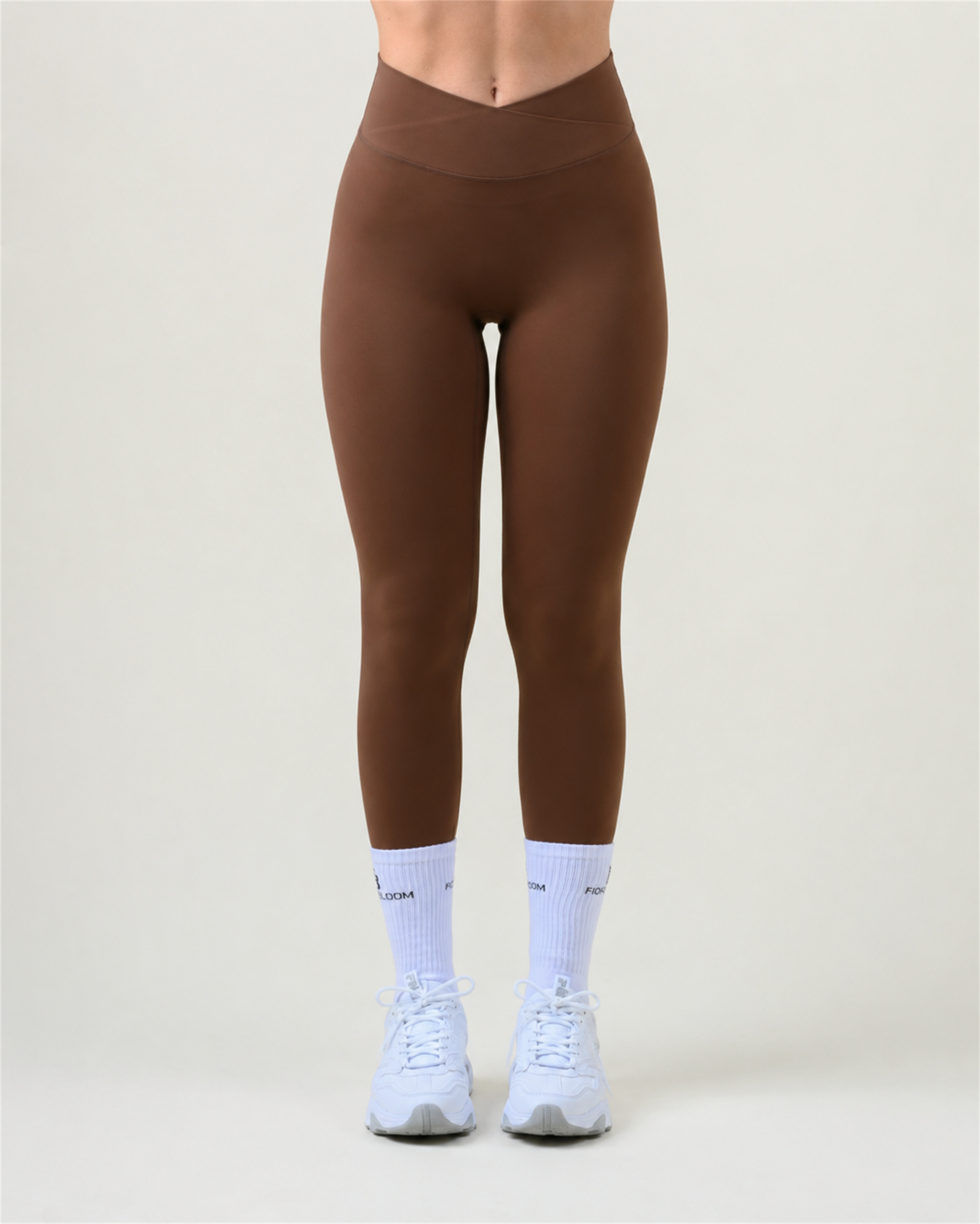SoftForm V-Shape Leggings in Espresso von Fiora Bloom – Titelbild, Frontansicht der Beine vor hellem Studiohintergrund, V-förmiger Bund sichtbar, dazu weisse Fiora Bloom Socken und weisse Sneaker.