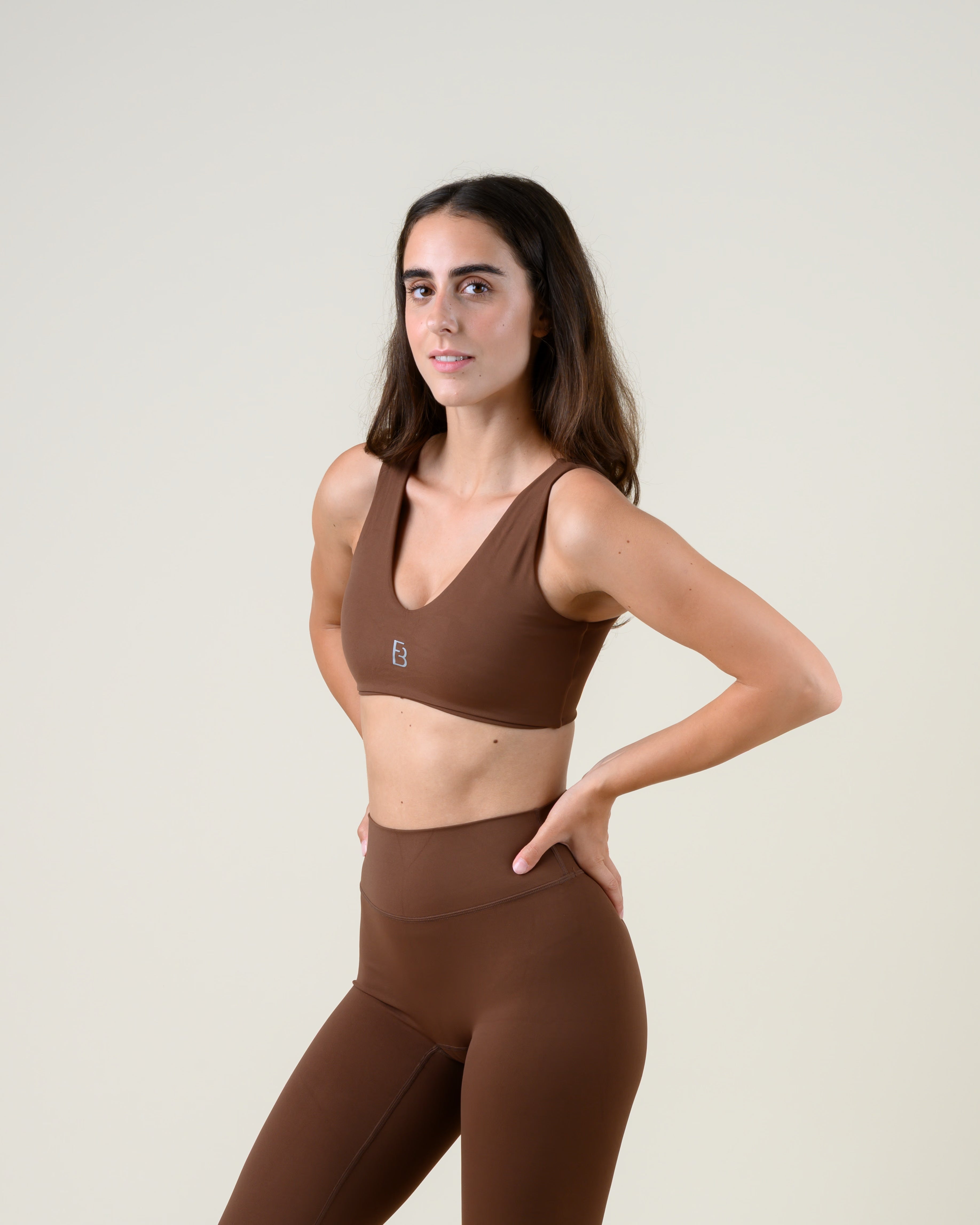 Soft Form V-Top in Espresso von Fiora Bloom – Dreiviertelansicht von vorne, zweite Pose, Hand in der Taille, Passform im Set mit der Leggings sichtbar.