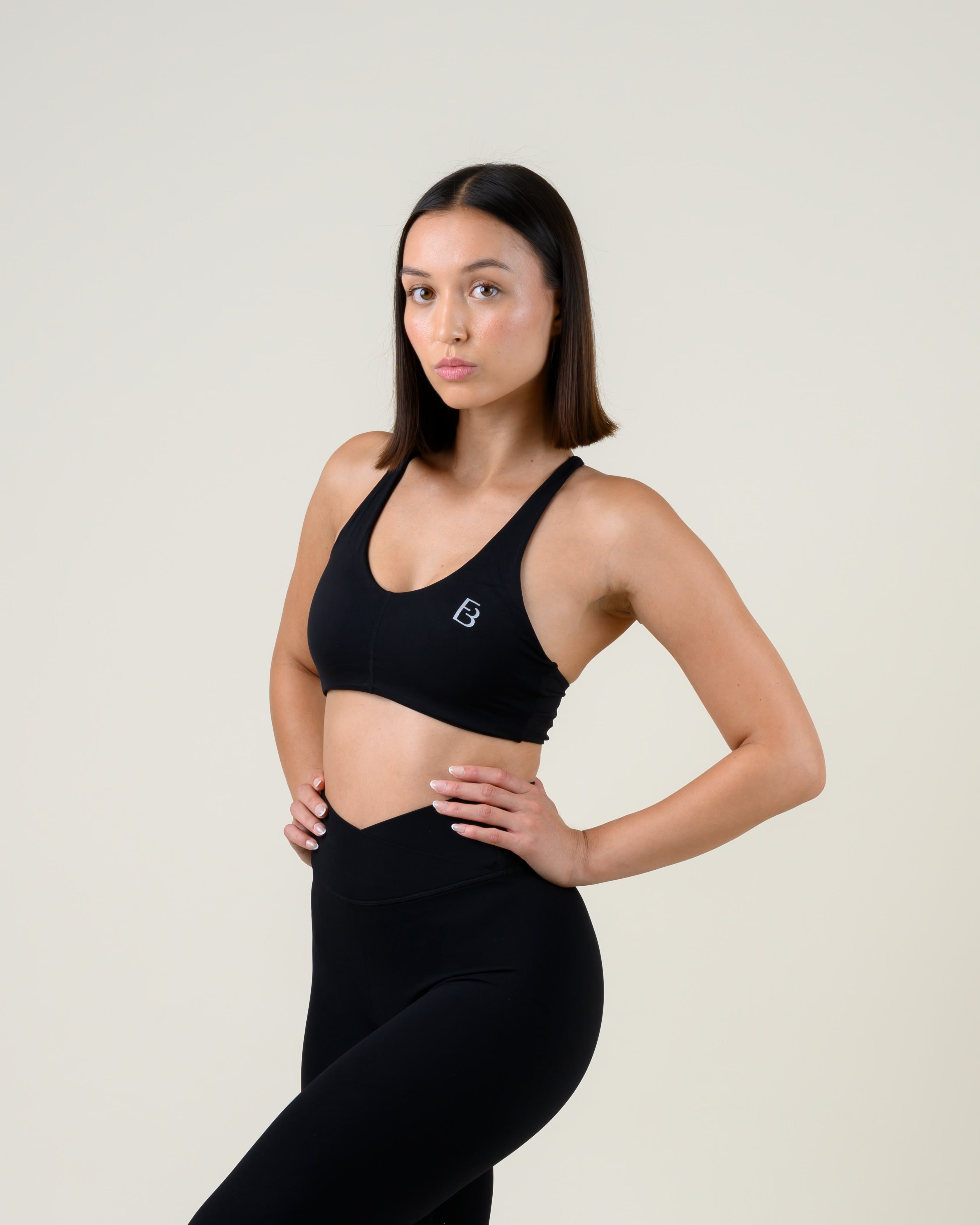 Soft Form Basic Top in Schwarz von Fiora Bloom – Dreiviertelansicht von vorne, Hand in der Taille, Passform an Brust und Rippenbogen sichtbar.