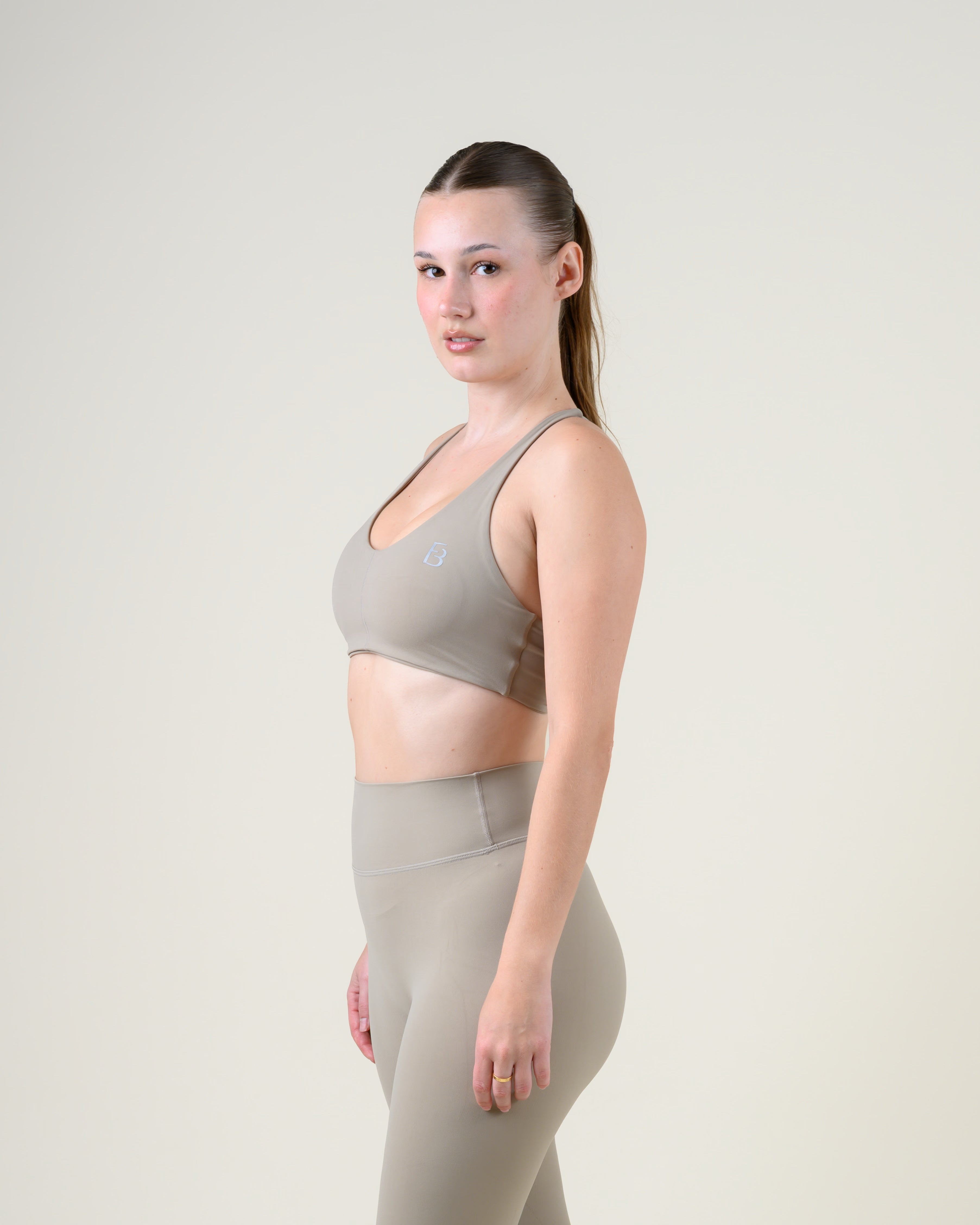 Soft Form Basic Top in Taupe von Fiora Bloom – Dreiviertelansicht von vorne, Oberkörper leicht gedreht, Träger und Ausschnitt sichtbar.