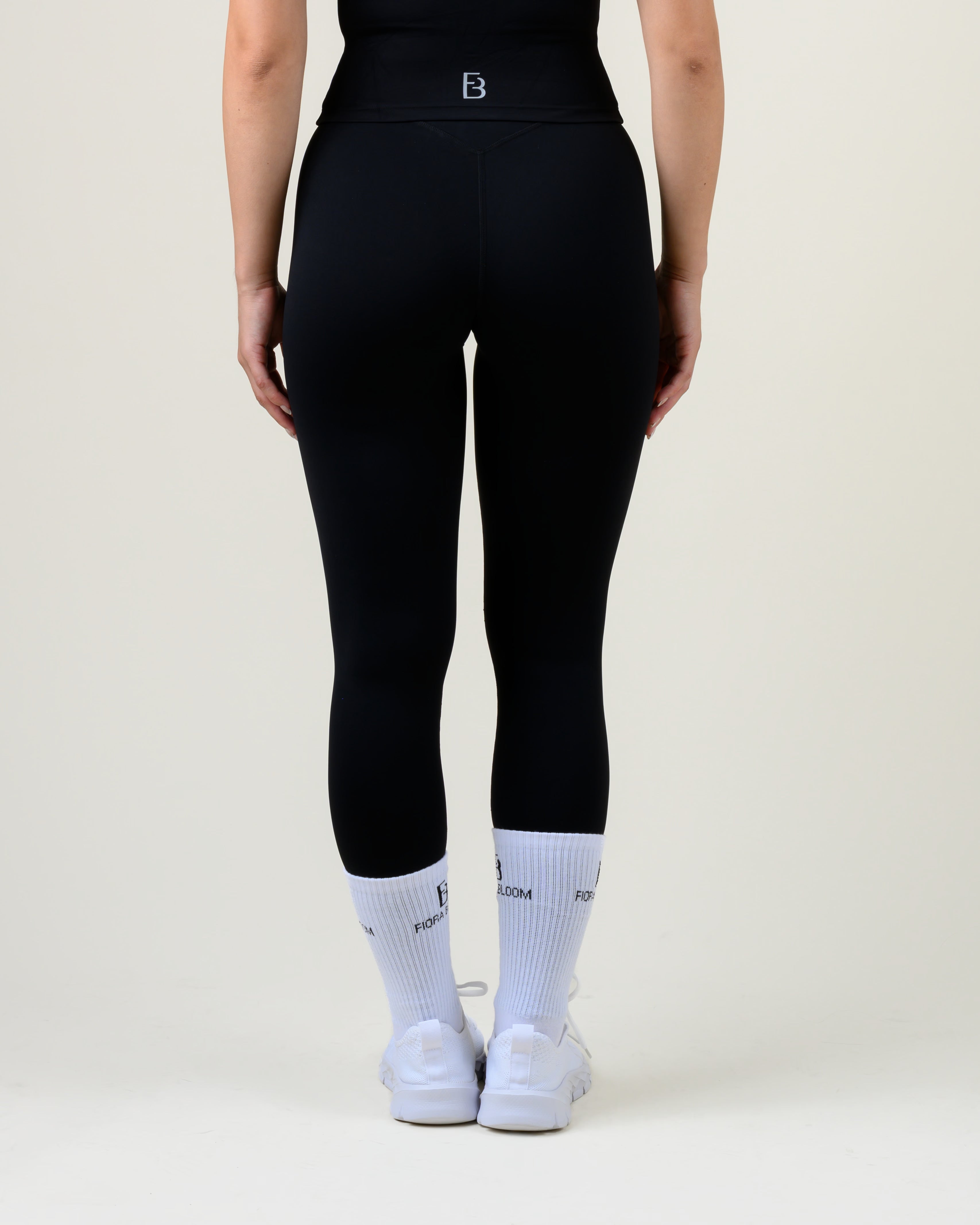 Soft Form High-Waist Leggings in Schwarz von Fiora Bloom – Rückansicht, Rückansicht mit geformter Bundnaht und Fiora Bloom Logo.