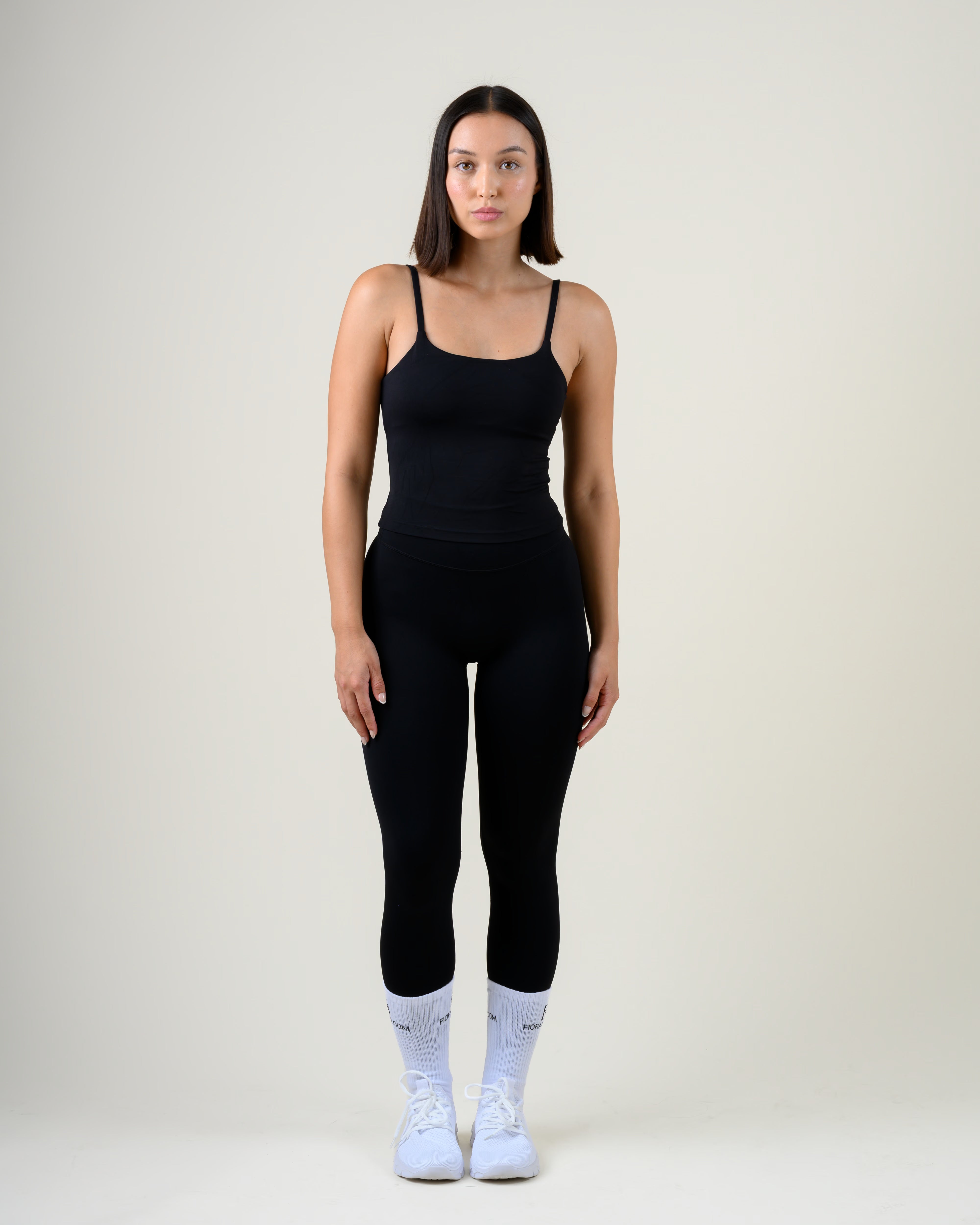 Soft Form Tanktop in Schwarz von Fiora Bloom – Ganzkörper-Look von vorne, kombiniert mit der Soft Form Leggings in Schwarz, weisse Socken und Sneaker.
