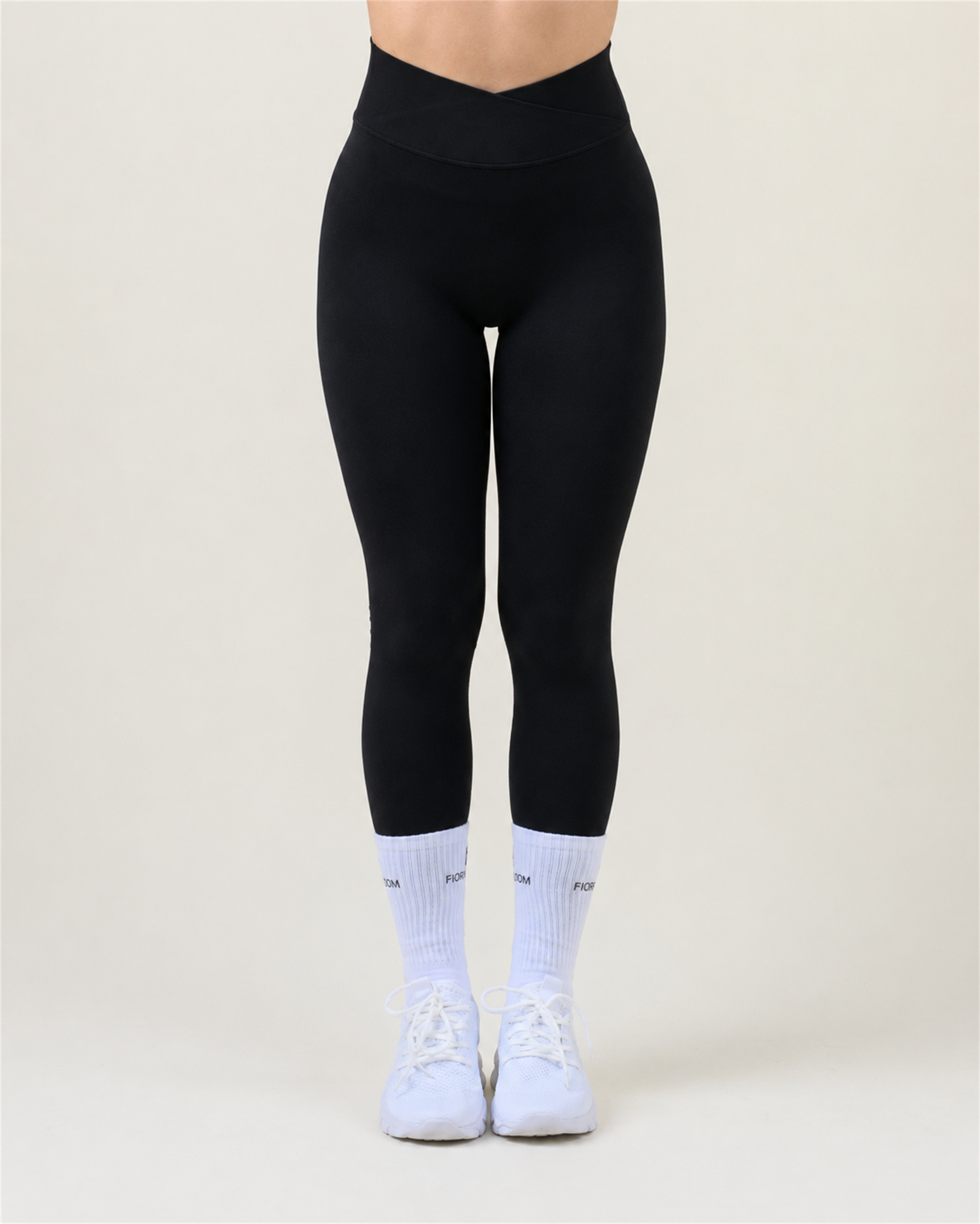SoftForm V-Shape Leggings in Schwarz von Fiora Bloom – Titelbild, Frontansicht der Beine vor hellem Studiohintergrund, V-förmiger Bund sichtbar, dazu weisse Fiora Bloom Socken und weisse Sneaker.