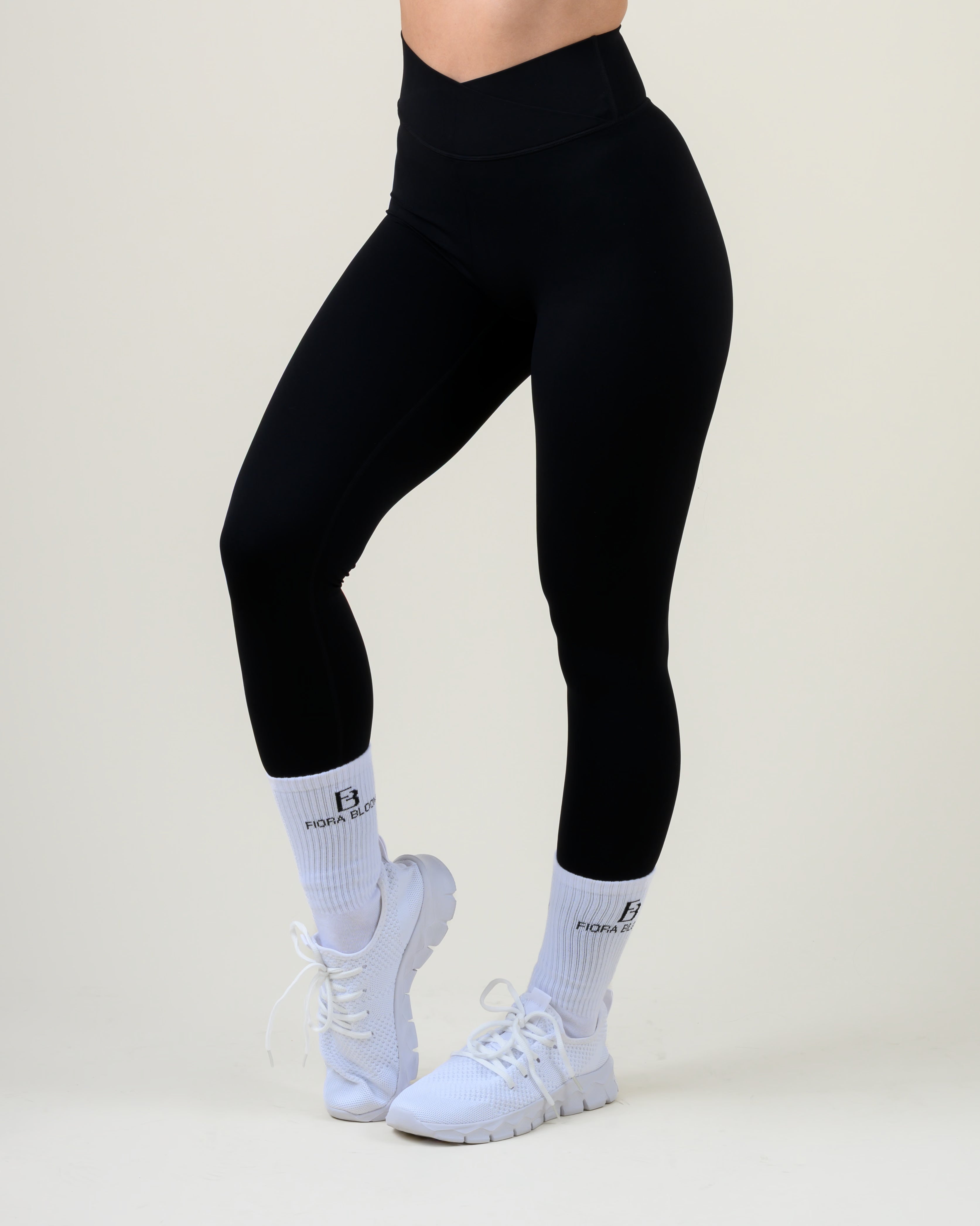 Soft Form V-Shape Leggings in Schwarz von Fiora Bloom – Dreiviertelansicht von vorne in Bewegung, Bein angewinkelt, Sitz an Hüfte und Oberschenkel sichtbar.