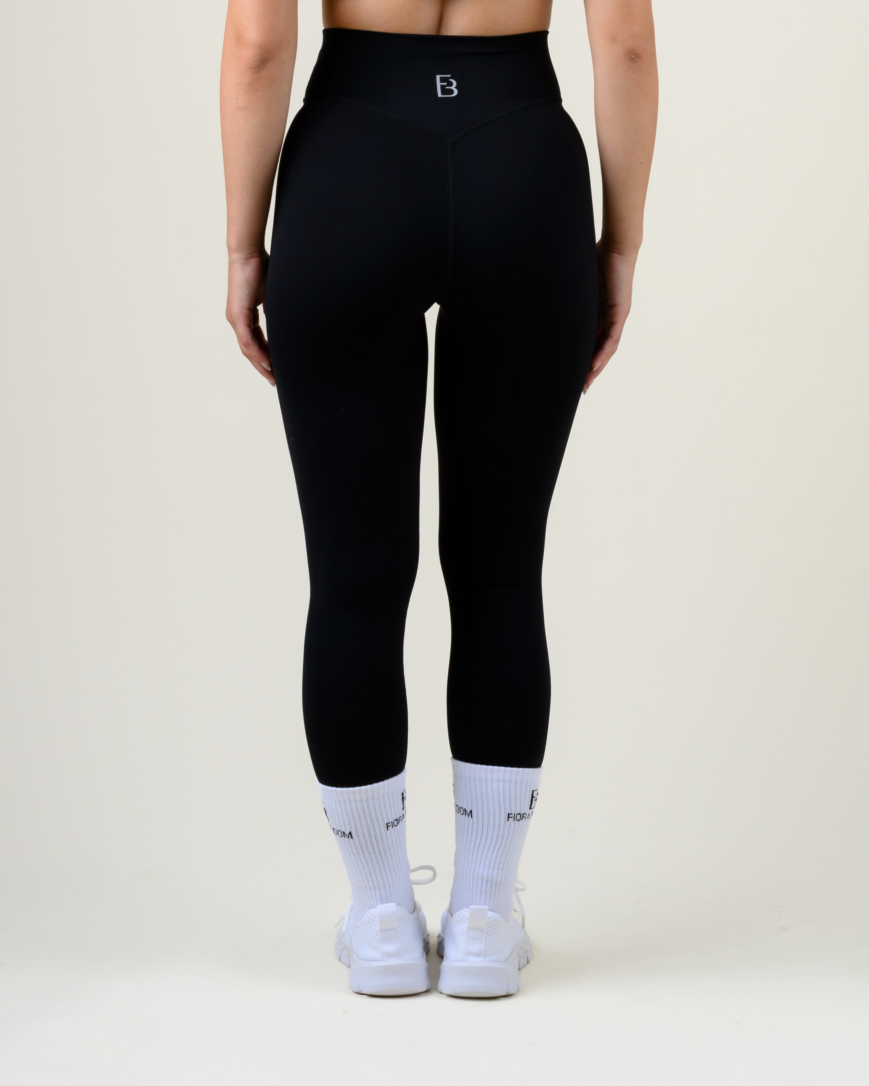 Soft Form V-Shape Leggings in Schwarz von Fiora Bloom – Rückansicht, Rückansicht mit geformter Bundnaht und Fiora Bloom Logo.