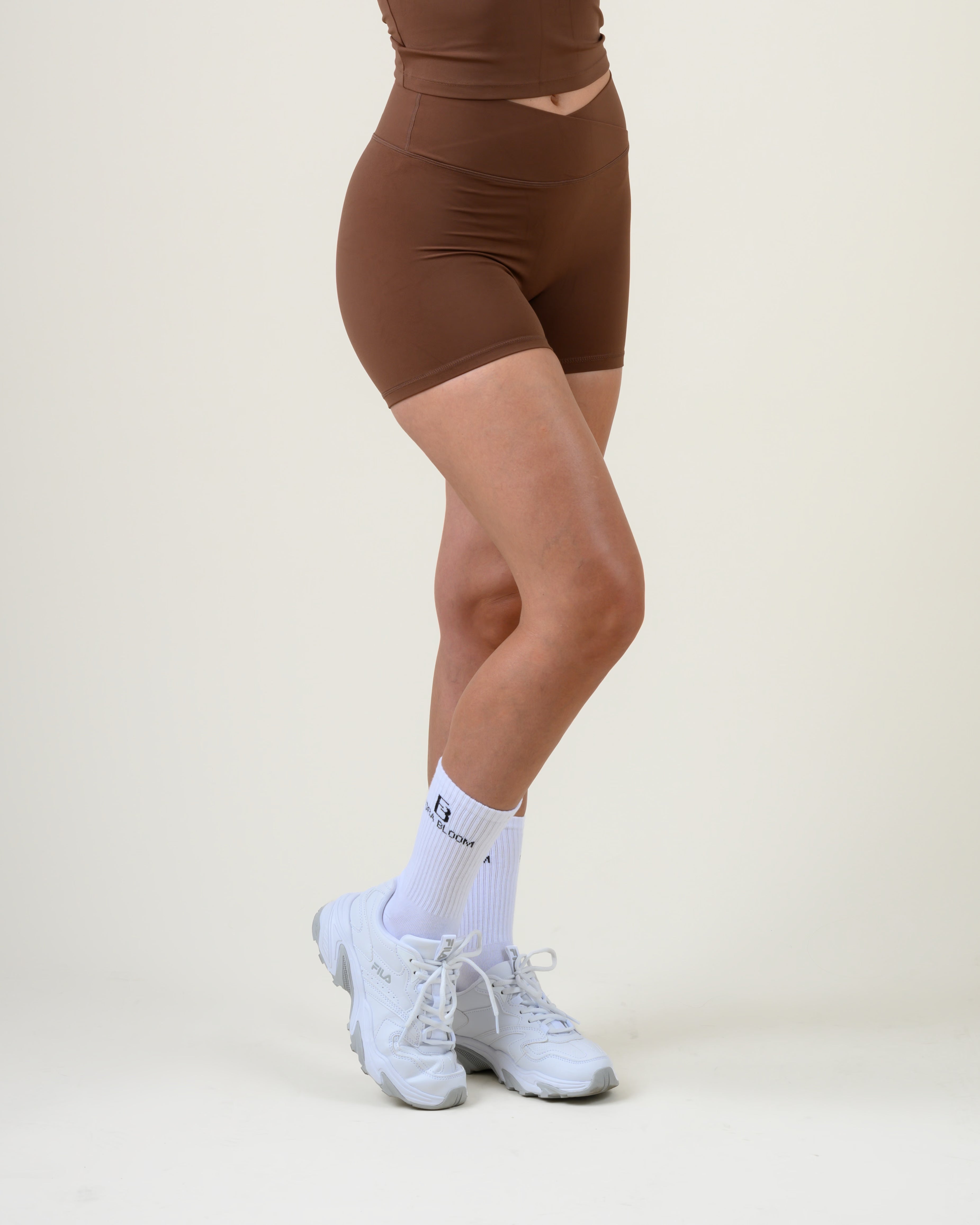 Soft Form V-Shape Shorts in Espresso von Fiora Bloom – Seitenansicht in Bewegung, Seitenprofil in Bewegung, Beinabschluss und Bundhöhe sichtbar.