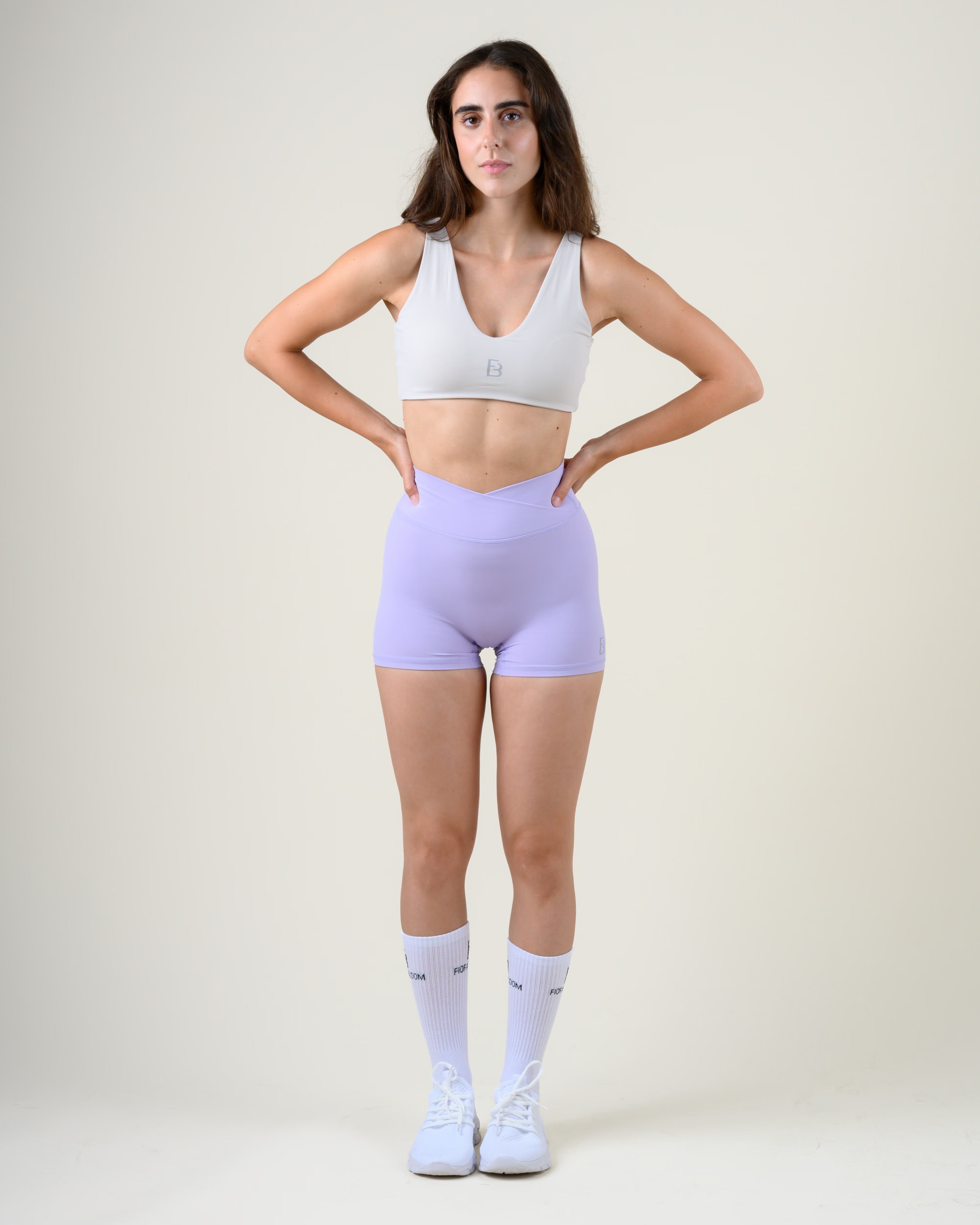 Soft Form V-Shape Shorts in Lila von Fiora Bloom – Ganzkörper-Look von vorne, kombiniert mit dem Soft Form V-Top in Lime, weisse Socken und Sneaker.