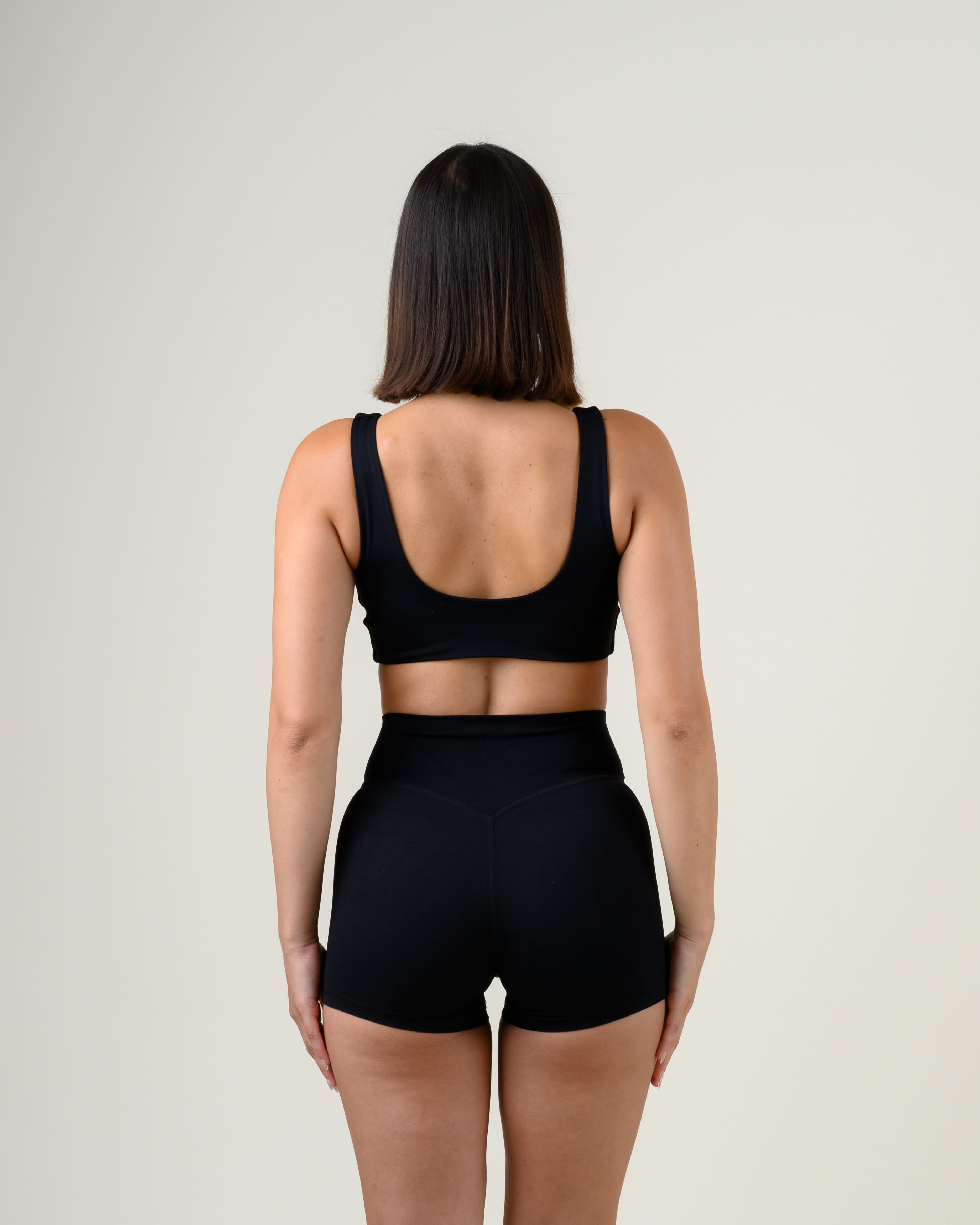 Soft Form V-Top in Schwarz von Fiora Bloom – Rückansicht mit offenem Rückenausschnitt, breite Träger und offener Rücken im Detail.