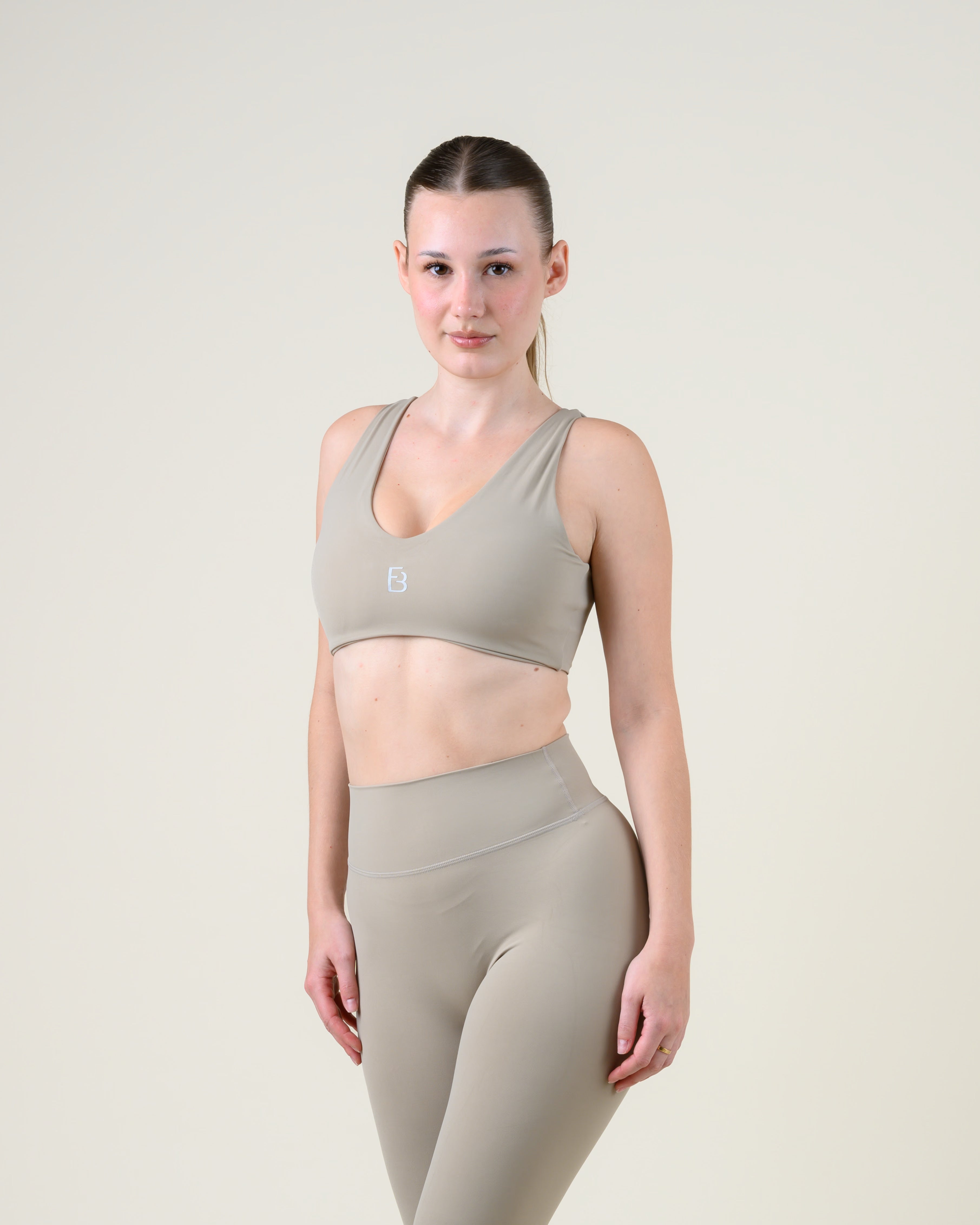 Soft Form V-Top in Taupe von Fiora Bloom – Dreiviertelansicht von vorne, zweite Pose, zweite Pose mit Blick zur Kamera, Trägerverlauf sichtbar.